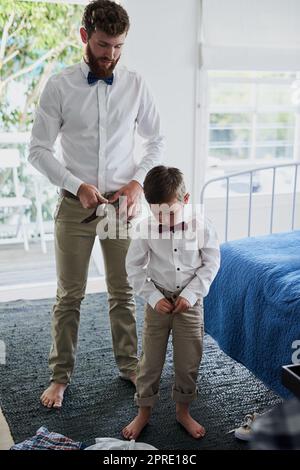 Ein entzückender kleiner Junge und sein Vater kleiden sich in passende Outfits. Stockfoto