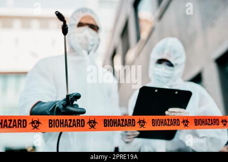 Covid, Pandemie und ein Team von Ärzten, Wissenschaftlern oder medizinischem Personal tragen Schutzanzüge, um die Ausbreitung des Virus an einer Quarantänestelle zu verhindern. Ersthelfer sterilisieren den infizierten Bereich. Stockfoto