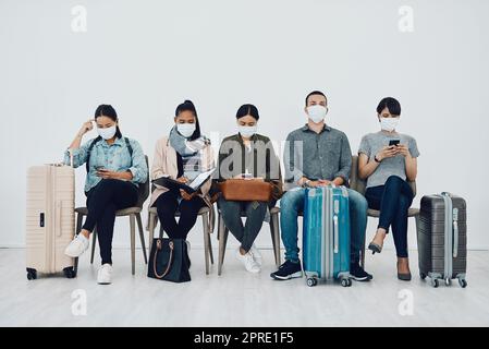 Reisen und Tourismus während der Pandemie mit Passagieren, die Masken tragen und sich sicher in der Schlange am Flughafen befinden. Gruppe von Personen in einer Abflughalle, bereit zum Einsteigen und gemäß Covid-Protokoll Stockfoto