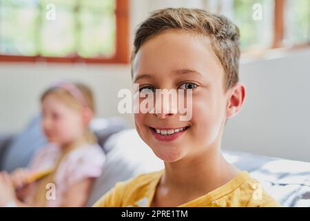 Das Abhängen mit seiner Schwester macht ihn glücklich. Porträt eines entzückenden kleinen Jungen im Wohnzimmer zu Hause. Stockfoto