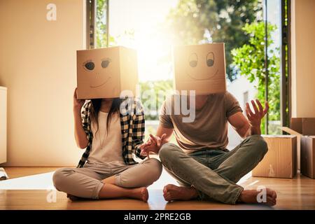 Sie sind ein Paar, das alles über Spaß und Unterhaltung weiß. Ein Paar trägt Kisten mit Smiley-Gesichtern, die auf ihren Köpfen gezeichnet sind. Stockfoto