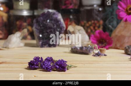 Amethyst-Kristalle mit Blumen auf dem Meditationstisch Stockfoto