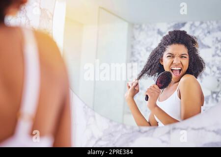 Fühlen Sie sich fabelhaft, sehen Sie fabelhaft aus. Eine attraktive junge Frau singt beim Haarbürsten im Badezimmer zu Hause. Stockfoto