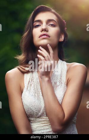 Lassen Sie sich von ihrer Schönheit verzaubern. Eine schöne junge Frau, die in der Natur posiert. Stockfoto