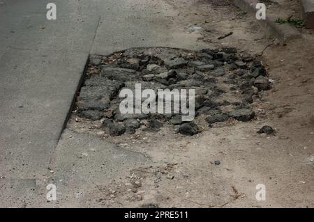 Ein Loch im Asphalt mit Bruchstücken von Asphalt Stockfoto