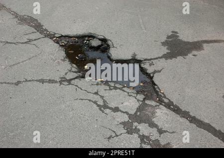 Eine Pfütze auf geknacktem Asphalt Stockfoto