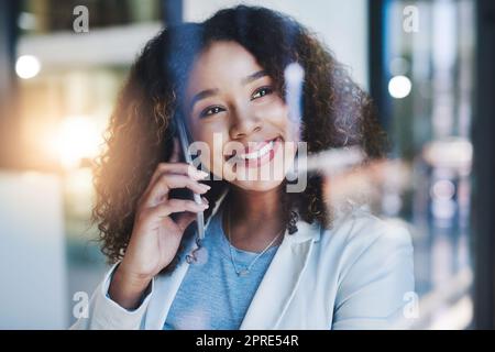 Jeder Anruf bringt sie dem großen Erfolg näher. Eine junge Geschäftsfrau, die im Büro auf einem Mobiltelefon spricht. Stockfoto