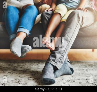 Eine dreiköpfige Familie, die sich zu Hause auf dem Sofa entspannt hat, hat sich für die Zeit der Familienzusammenbindung entschieden. Stockfoto