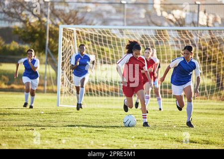 Sportmannschaft, Frauenfußball und Kickball auf dem Spielfeld in einem Turnier. Fußball, Wettkampf und sportliche Teenagergruppe spielen auf dem Gras. Fit-Jugendliche kämpfen um den Sieg bei der Schulmeisterschaft. Stockfoto