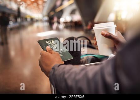 Warten auf den Boarding-Anruf. POV schoss einen nicht erkennbaren Mann, der seinen Pass und seine Bordkarte bei einem Kaffee im Flughafen hielt. Stockfoto