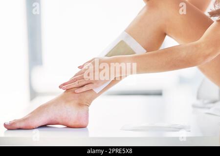 Entfernen Sie unerwünschte Haare. Nahaufnahme einer unkenntlichen Frau, die zu Hause im Badezimmer ihre Beine wachst. Stockfoto