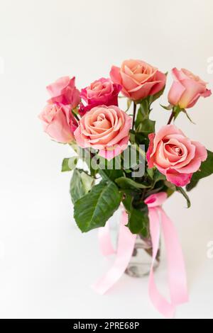 Schöne, leuchtend rosa-rote Rosen, Blumen in einer Vase, Seitenansicht, vertikales Foto. Blumen für die Feiertage. Stockfoto