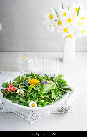 Frühlingstisch mit Blumen, Kräutern und Pflanzen. Wilder Knoblauch, Brennnessel, Löwenzahn und andere Heilkräuter sowie wilde essbare Pflanzen, die im Ohr wachsen Stockfoto