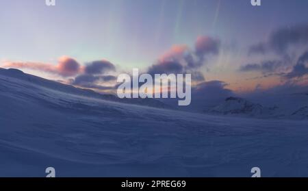 Die isländische Landschaft in der Dämmerung, am Rand eines Gletschers mit den leuchtenden Farben der Nordlichter/Aurora Borealis am Himmel Stockfoto