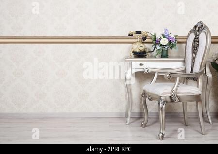 Ein Fragment eines retro Interieur mit einem Sessel und einen Schreibtisch, auf dem ein Telefon und eine Vase mit Blumen befindet. Stockfoto