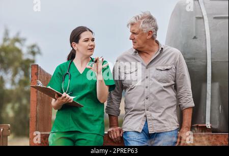 Gemeinsam hoffen wir, die Tiergesundheit für eine nachhaltige Landwirtschaft zu verbessern. Ein Tierarzt, der mit einem erwachsenen Mann auf seiner Farm spricht Stockfoto