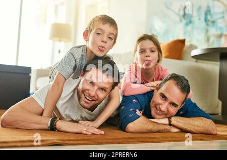 Es gibt immer Zeit für die Familie. In voller Länge Porträt einer liebevollen vierköpfigen Familie, die auf ihrem Wohnzimmerboden liegt. Stockfoto