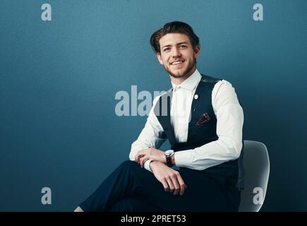 Ich bin jung und voller Ehrgeiz. Studioaufnahme eines hübschen jungen Geschäftsmannes, der vor blauem Hintergrund posiert. Stockfoto