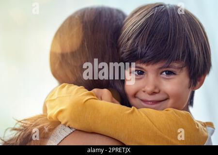 Diese Mutter-Sohn-Bindung war schon immer eine besondere. Ein entzückender kleiner Junge umarmte seine Mutter zu Hause liebevoll. Stockfoto