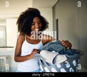 Ordnung in ihrem Zuhause, angefangen bei der Wäsche. Eine attraktive junge Frau, die zu Hause die Wäsche macht. Stockfoto