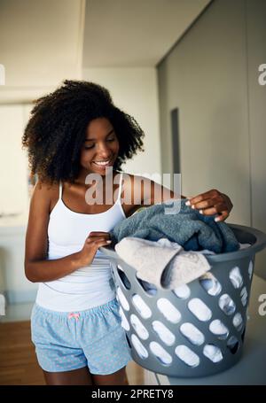 Diese wird sortiert und dann gewaschen. Eine attraktive junge Frau macht die Wäsche zu Hause. Stockfoto