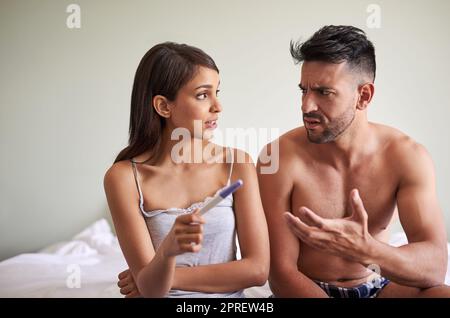 Was werden wir tun? Ein junges Ehepaar wartet auf die Ergebnisse eines Schwangerschaftstests in ihrem Schlafzimmer zu Hause. Stockfoto