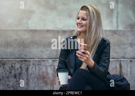 Ich kann mir keine Welt ohne Instant Messaging einleben lassen. Eine attraktive Frau, die in der Stadt ein Mobiltelefon benutzt. Stockfoto