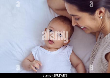 Mütter wie ein Engel, weil sie über mich wacht. High-Angle-Aufnahme einer jungen Frau, die sich zu Hause mit ihrem kleinen Jungen verklebt. Stockfoto