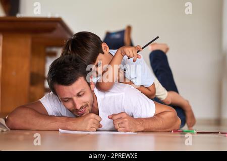 Seinem Sohn die größte Geschenkzeit zu geben. In voller Länge ein Vater, der mit seinem Sohn zu Hause auf dem Boden spielt. Stockfoto