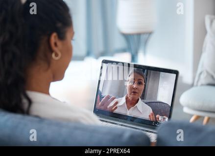 Hatten Sie andere Symptome? Eine nicht wiedererkennbare Frau, die sitzt und einen Laptop für eine Online-Beratung mit ihrem Psychologen benutzt Stockfoto