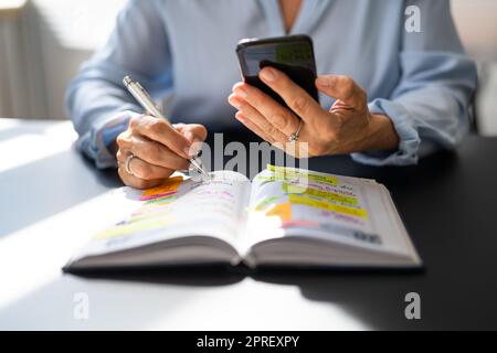 Kalenderplan In Papier Und Am Telefon Stockfoto
