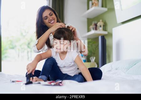 Machen Sie sich bereit für einen unterhaltsamen Tag. Eine Mutter stylen ihre kleinen Töchter Haare, während sie mit Make-up zu Hause spielen. Stockfoto