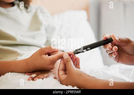 Diabetes, Diabetiker und Blutzuckerspiegel der Mutter bei einem chronisch kranken Kind zu Hause. Nahaufnahme der mutter, die den Blutzucker ihres Kindes im Bett oder im Schlafzimmer misst, überprüft und überwacht Stockfoto