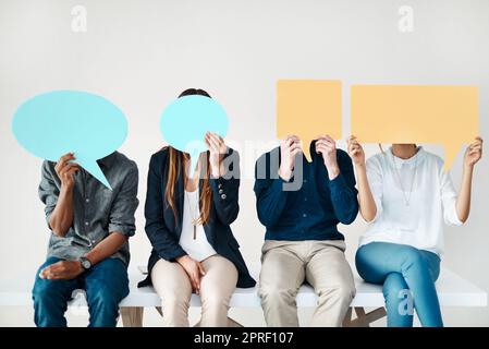 Wir wollen gehört werden. Eine vielfältige Gruppe kreativer Mitarbeiter hält Sprechblasen in sich. Stockfoto