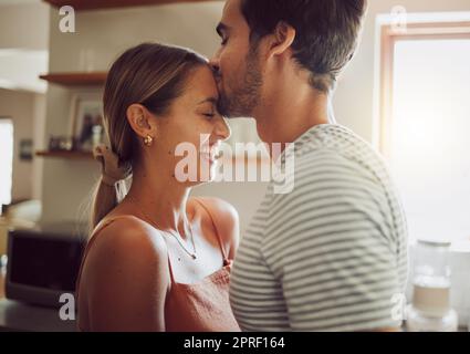 Liebevolles, liebevolles und romantisches Paar in einer glücklichen Beziehung zusammen in der Küche zu Hause. Mann und Frau, die einen Moment des Glücks, der Romantik und der Liebe miteinander verbringen. Stockfoto