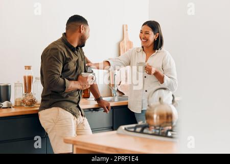 Verspielter Kaffee und liebevolles Paar, das sich in der Küche zuhause verbindet und Spaß miteinander hat. Ein lächelndes, verliebtes und sorgenfreies Paar, das lacht und einen romantischen Moment genießt, während es das Wochenende genießt. Stockfoto