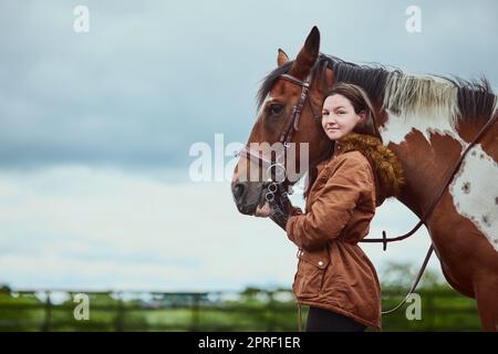 Es braucht Selbstvertrauen, um sich um ein Tier zu kümmern. Ein Teenager-Mädchen, das neben ihrem Pony auf einem Bauernhof steht. Stockfoto
