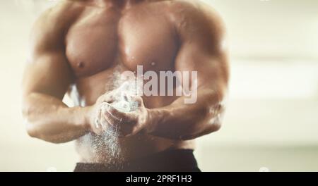 Achten Sie darauf, dass es keine Rutsch-ups. Ein unkenntlich junger Mann pudert seine Hände während eines Trainings in der Turnhalle. Stockfoto