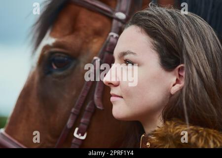 Leben durch die Augen eines Ponys. Ein Teenager-Mädchen, das neben ihrem Pony auf einem Bauernhof steht. Stockfoto