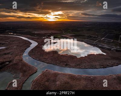 Luftaufnahme des Utxesa-Reservoirs bei Sonnenuntergang im Winter mit rotem Himmel (Segrià, Lleida, Katalonien, Spanien) ESP: Vista aérea del embalse de Utxesa Stockfoto