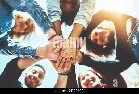 Als Team können Sie viel mehr erreichen. Hochwinkelporträt einer vielfältigen Gruppe von College-Freunden, die draußen mit ihren Händen in einem Gehege stehen. Stockfoto