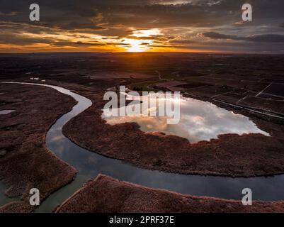 Luftaufnahme des Utxesa-Reservoirs bei Sonnenuntergang im Winter mit rotem Himmel (Segrià, Lleida, Katalonien, Spanien) ESP: Vista aérea del embalse de Utxesa Stockfoto