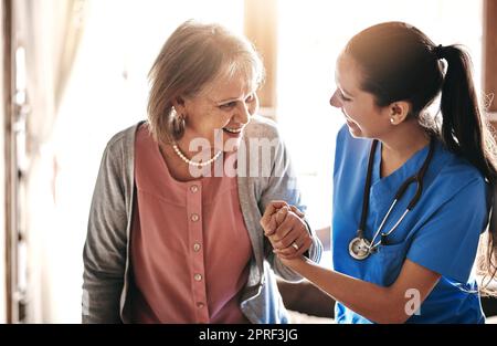 Ich bin hier, um Ihnen bei jedem Schritt zu helfen. Ein Betreuer, der einem älteren Patienten in einem Pflegeheim hilft. Stockfoto