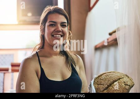 Frisches Brot für diejenigen, die es frisch mögen. Eine junge Frau, die in ihrer Bäckerei arbeitet. Stockfoto