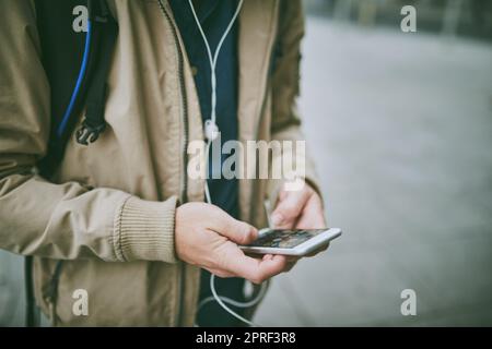 Seine Lieblingsmusik begleitet ihn auf dem Weg zur Arbeit. Aufnahmen aus dem Blickwinkel eines unbekannten Mannes, der Musik auf seinem Handy hörte, während er durch die Stadt ging. Stockfoto