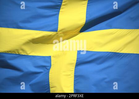 Die schwedische Nationalflagge in den Farben Blau und Gelb winkt im Wind. Die Krone ist die Währung Schwedens. Stockfoto