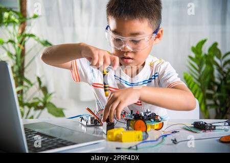 Asiatischer Junge, der zu Hause das Heimprojekt des Arduino-Roboters zusammenführt Stockfoto