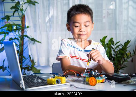 Asiatischer Junge, der zu Hause das Heimprojekt des Arduino-Roboters zusammenführt Stockfoto