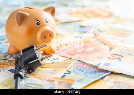 Elektrostecker, Sparschwein und Euro-Geld. Konzept steigender Strompreise. Stockfoto