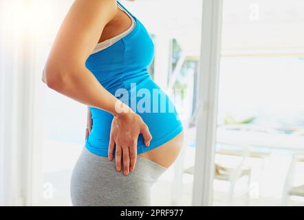 Der Countdown zur Mutterschaft. Eine Schwangerin wartet vor einem Fenster in Erwartung zu Hause. Stockfoto